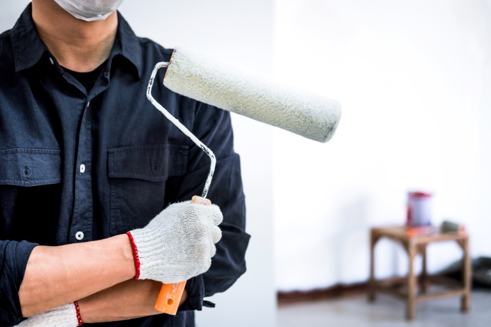 male-painter-with-arm-crossed-holding-paint-roller